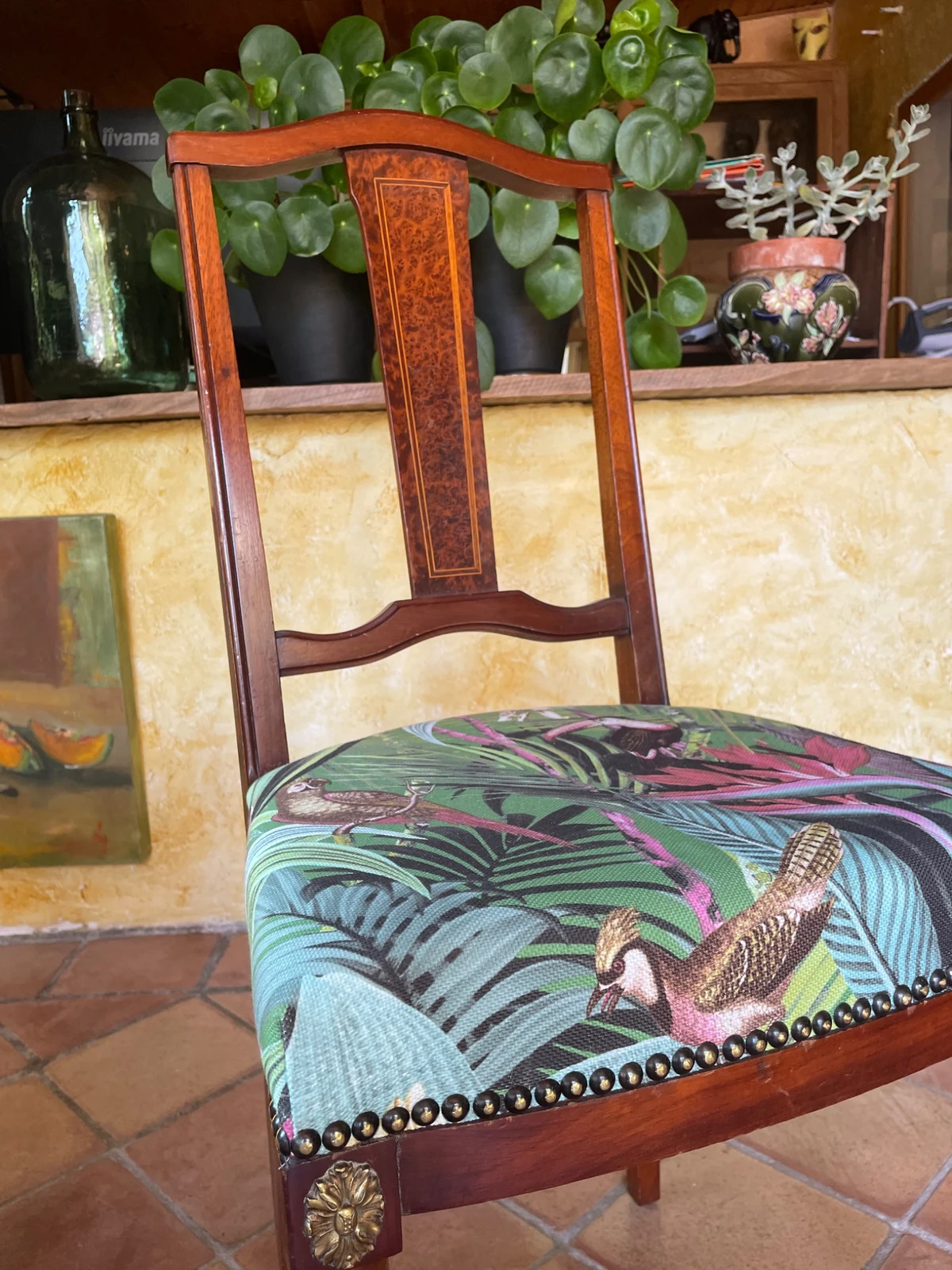 Détail du tissu à motifs d’oiseaux et de feuillages et de la finition cloutée de la chaise style Empire